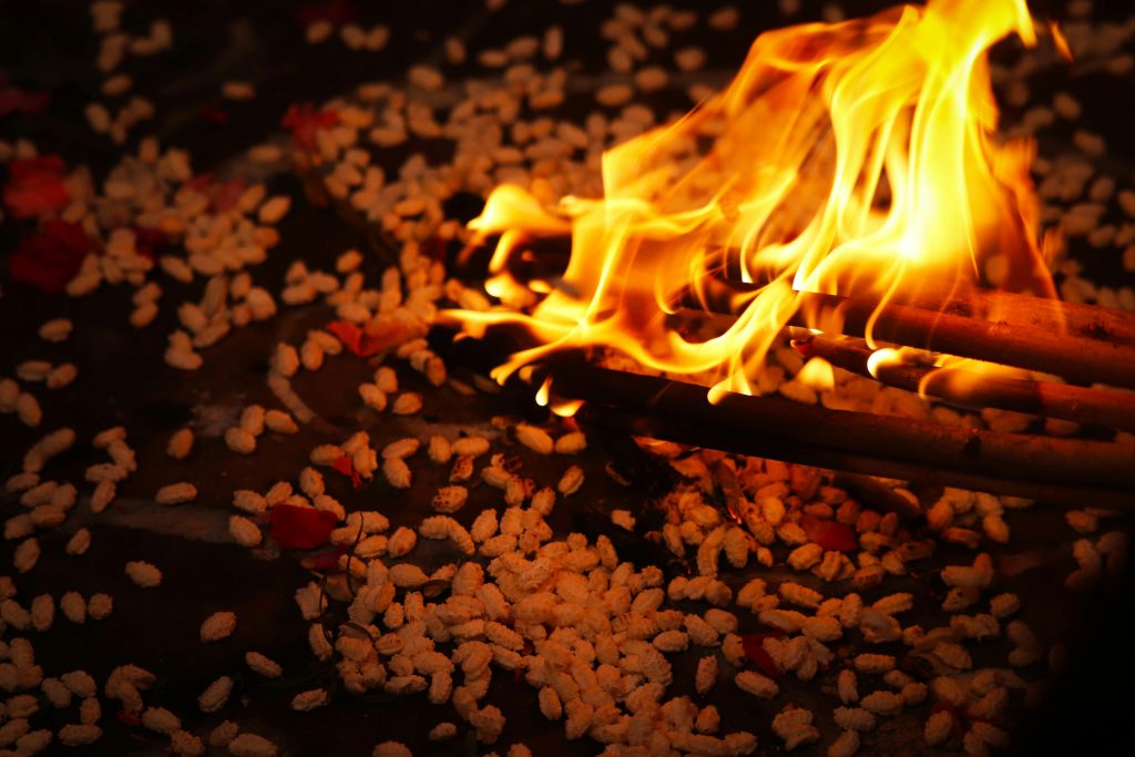 Capturing the vibrant flames of a Hindu ritual fire surrounded by uncooked rice grains and offerings.